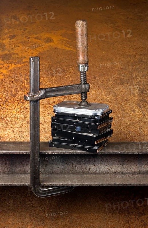 Some hard disk drives compressed with a screw clampin rusty back