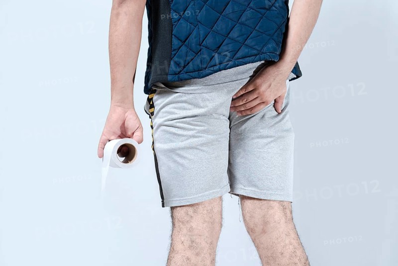 Man with diarrhea holding toilet paper an his anus