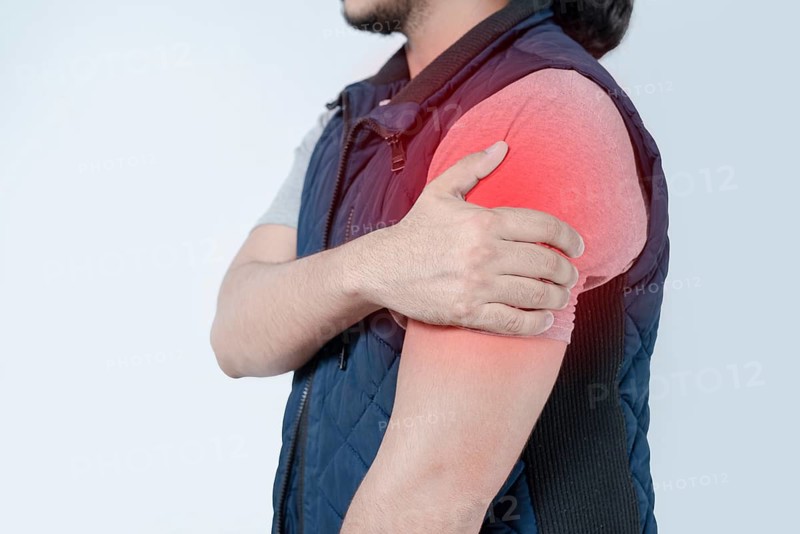 Unrecognizable person with shoulder pain on isolated. Person in pain with arm pain highlighted in red on isolated