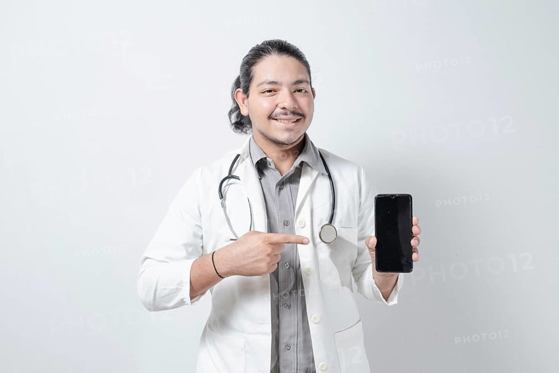 Smiling young doctor pointing at the phone