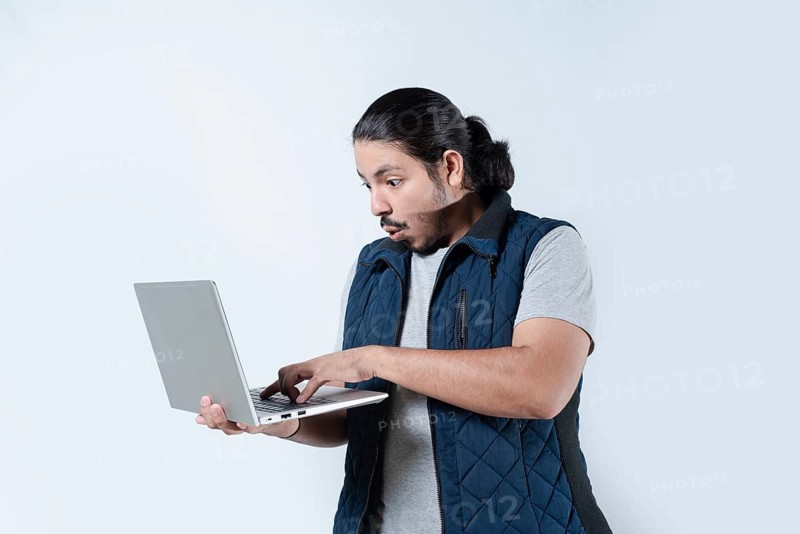 Man surprised looking at the computer he is holding on isolated