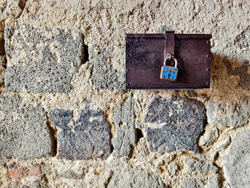 A metal box with a padlock hangs on a rough stone wall Styria Austria