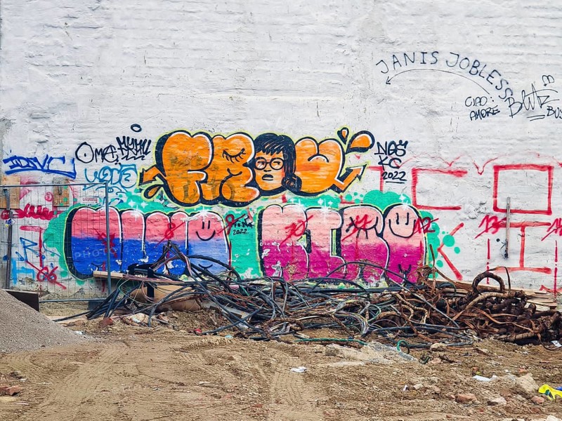 A hodgepodge of colourful graffiti adorns a white wall with cables on the floor Mariahilferstrasse Vienna Austria