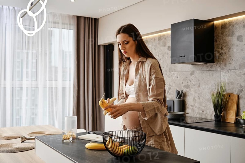 Pregnant woman preparing healthy snacks in modern kitchen with fresh fruits and natural light