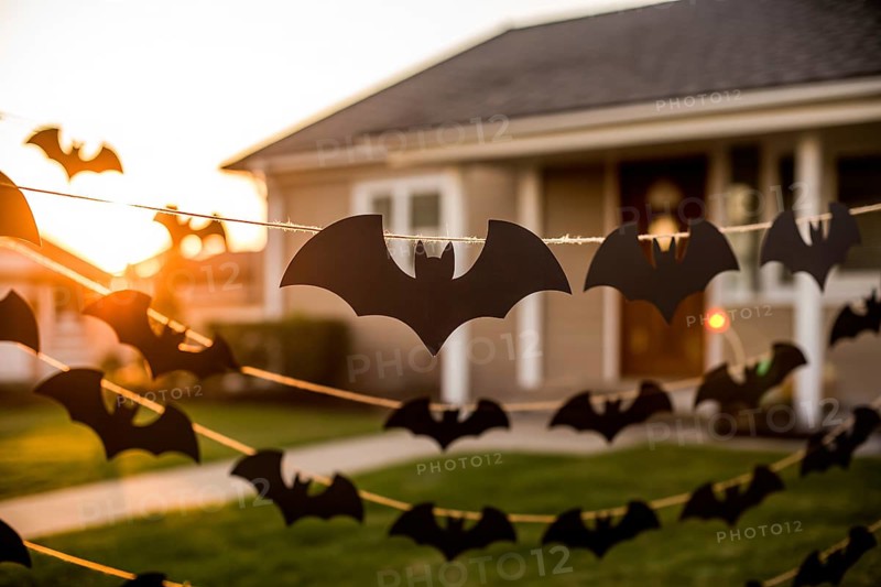 Black paper bat garland decorating house exterior. Bright sunny day Halloween outdoor decoration. Generative ai, AI generated
