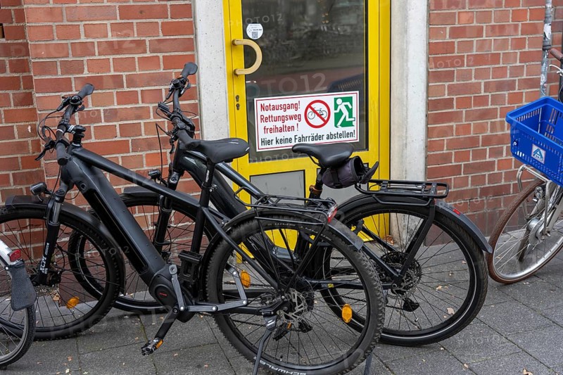 Bicycle traffic in Münster, bicycles parked on the pavement, in front of an emergency exit, which is also labelled as such, North Rhine-Westphalia, Germany