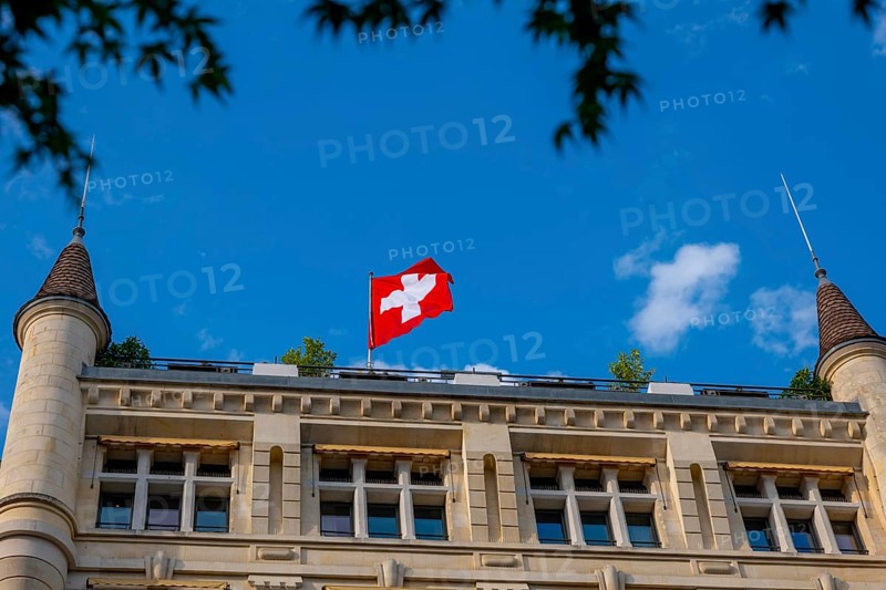 Beautiful Swiss Flag on a Old Building with Towers Against Blue Sky in a Sunny Summer Day in Lausanne, Vaud, Switzerland