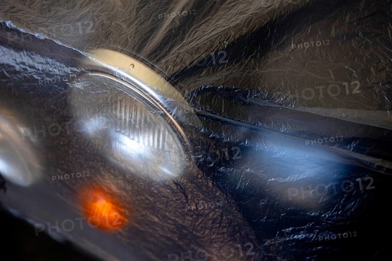 Car Lamps on the Front of a an Old Classic Car Covered with Plastic Protection in Switzerland
