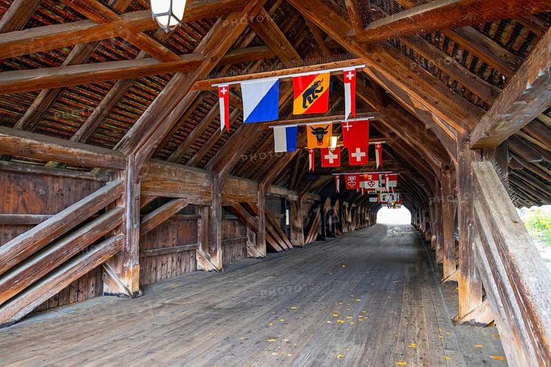 Inside the Old Historical Covered Wood Bridge Holzbrücke with Swiss Canton Flags over River Aare in a Sunny Day in Olten, Canton Solothurn, Switzerland