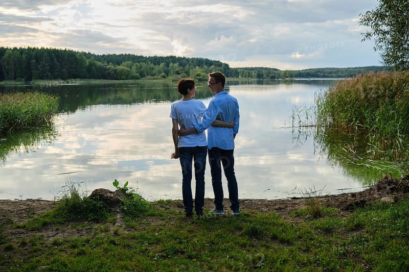 Couple enjoying a serene moment by the lake during golden hour at a tranquil nature spot