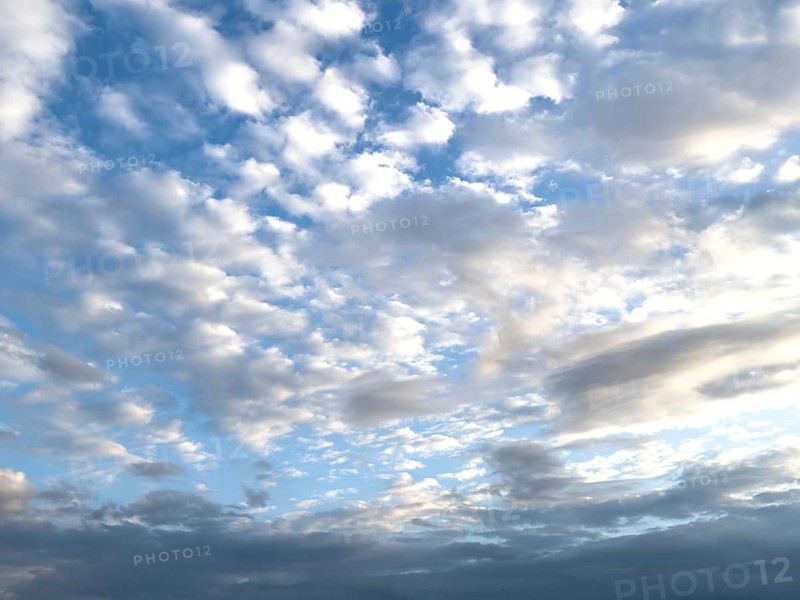 View at dusk on top large cloud field of cirrocumulus clouds drifting at high altitude white clouds, below and to the right altostratus, international