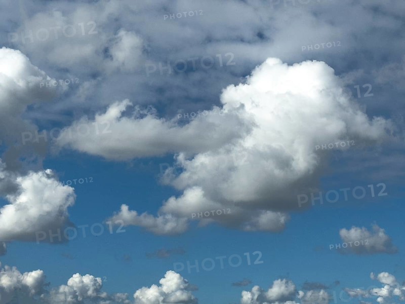 Cumulus clouds at the bottom edge of the image, large white cumulonimbus cluster cloud towering in the centre of the image, altocumulus above, international