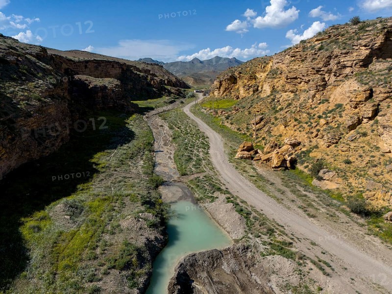 A path leads through a rocky valley with a narrow river flowing through the landscape, aerial view, on the way to Angel's Canyon, Dashtakar, Ararat Province, Armenia