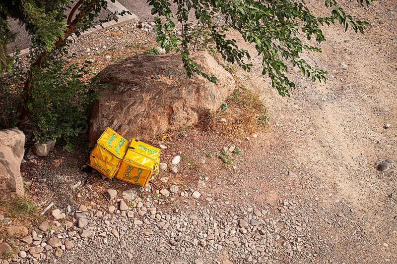 08/25/2025 Georgia, Tbilisi, Delivery packages, Glovo company, left on stony ground, near bushes, outdoors, no people