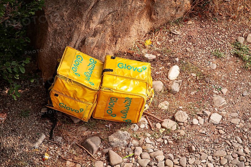 08/25/2025 Georgia, Tbilisi, Delivery packages, Glovo company, left on stony ground, near bushes, outdoors, no people