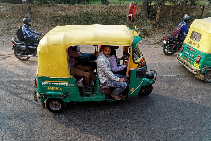 Yellow and green rickshaw with riders on a busy road, accompanied by motorcyclists, Agra, Jodhpur, Rajasthan, North India