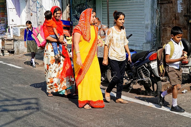 Udaipur, Rajasthan, North India, Asia, Women in colourful saris and children walking along a busy street