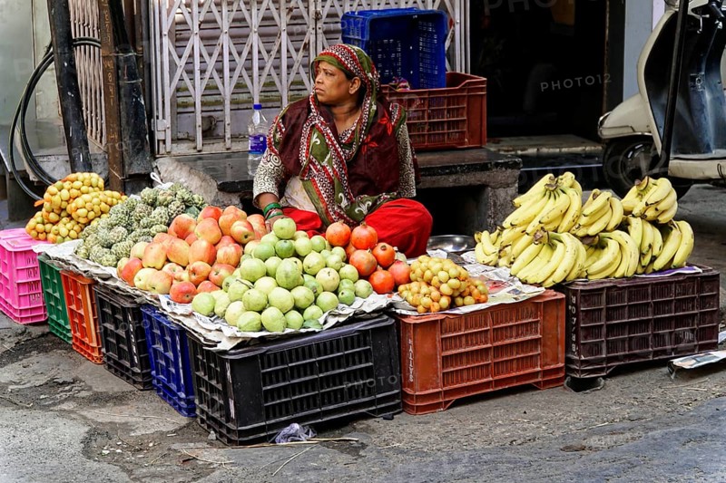 Udaipur, Rajasthan, North India, Asia, woman selling various fruits in plastic boxes at a market stall