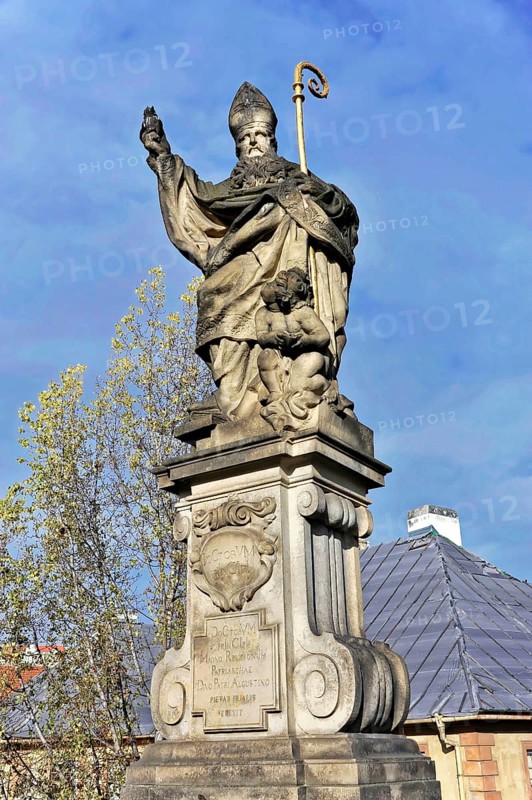 Statue on Charles Bridge, Old Town, UNESCO World Heritage Site, Prague, Czech Republic, Europe, Stone statue of a bishop with a child on an ornate pedestal against a blue sky