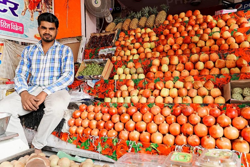 Kota, Rajasthan, North India, Asia, Vendor sitting at a market stall with a colourful selection of apples and other fruits, India