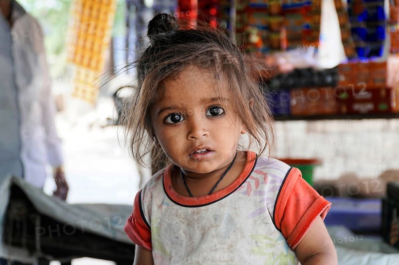 Kota, Rajasthan, North India, Asia, Little girl with a curious look in front of a colourful scenery, India