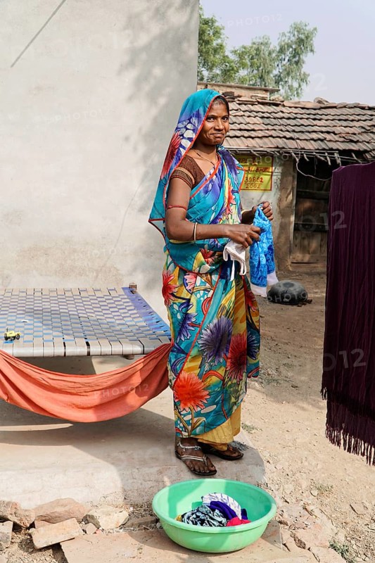 Kota, Rajasthan, North India, Asia, A woman in a colourful garment washes clothes in a rural courtyard, India