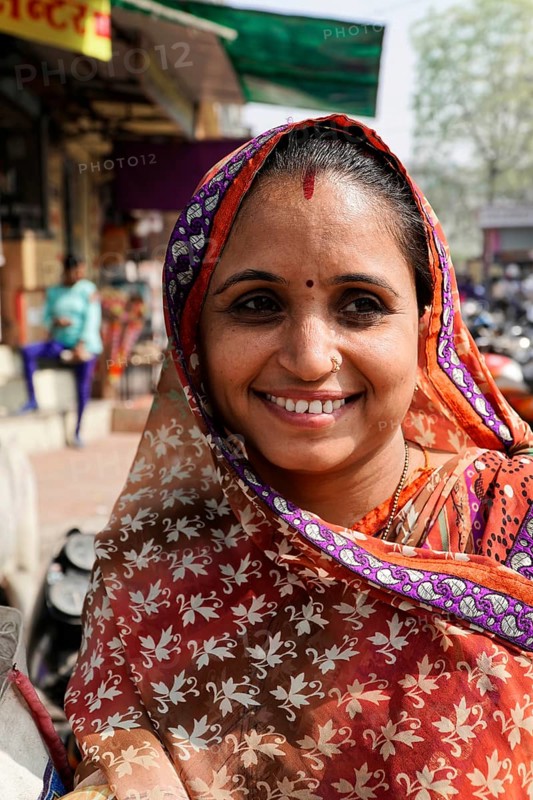 Kota, Rajasthan, North India, Asia, Smiling woman in traditional Indian sari in front of a busy street, India