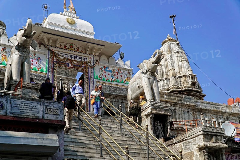 Entrance to Jagdish Temple, Udaipur, people climb the steps to a temple flanked by statues under a clear sky, Rajasthan, North India, India, Asia, Temple with imposing elephant sculptures under a clear blue sky