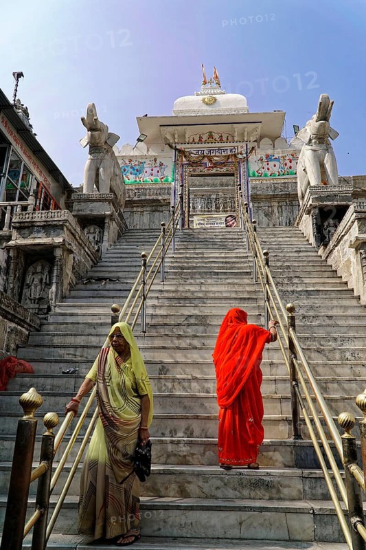 Entrance to Jagdish Temple, Udaipur, people climb the steps to a temple, flanked by statues under a clear sky, Rajasthan, North India, India, Asia, Women in saris climb the stairs of a traditional temple, flanked by elephant statues