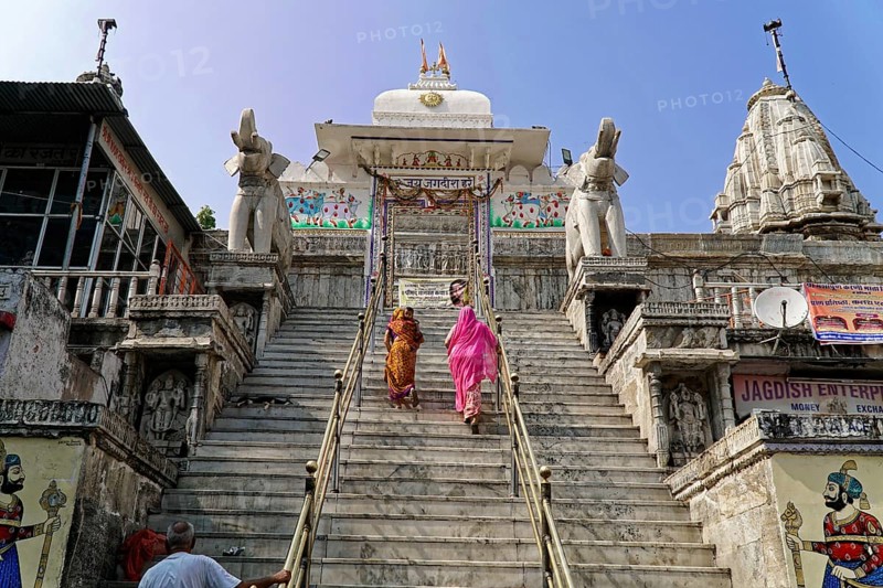 Entrance to Jagdish Temple, Udaipur, People climbing the steps to a temple flanked by statues under a clear sky, Rajasthan, North India, India, Asia, Traditional temple on a hill with majestic elephant statues and colourful murals, Sky clear