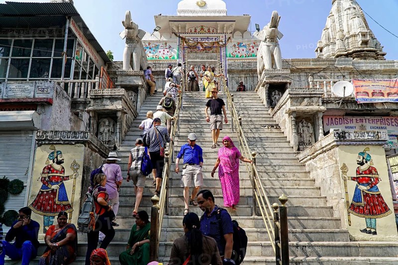 Entrance to Jagdish Temple, Udaipur, People climbing the steps to a temple flanked by statues under a clear sky, Rajasthan, North India, India, Asia, A busy temple in India with numerous visitors walking up and down the stairs