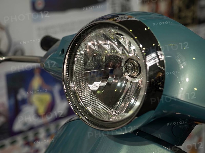 Close-up view of a retro scooter headlight with shiny chrome and a blue housing, dortmund, deutchland