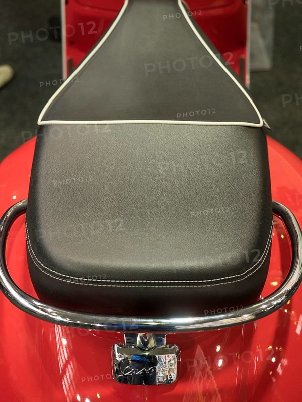Black motorbike seat with white stitching on red base and chrome handle, dortmund, deutchland