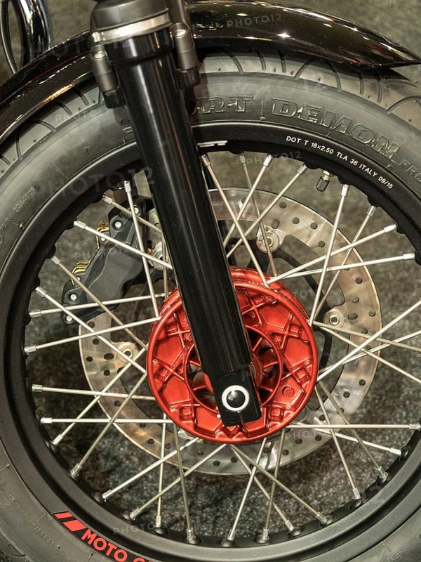 Close-up of a motorbike tyre with red brake caliper and spokes on dark ground, dortmund, germany