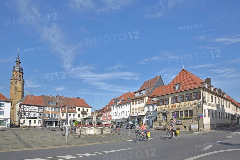 Market square with historic Schlundhaus, cyclist, steeple of the Church of the Assumption of the Virgin Mary, Bad Königshofen, Rhön, Lower Franconia, Franconia, Bavaria, Germany