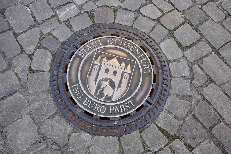 Round manhole cover with town coat of arms and inscription, paving stones, ground, Ochsenfurt, Lower Franconia, Franconia, Bavaria, Germany