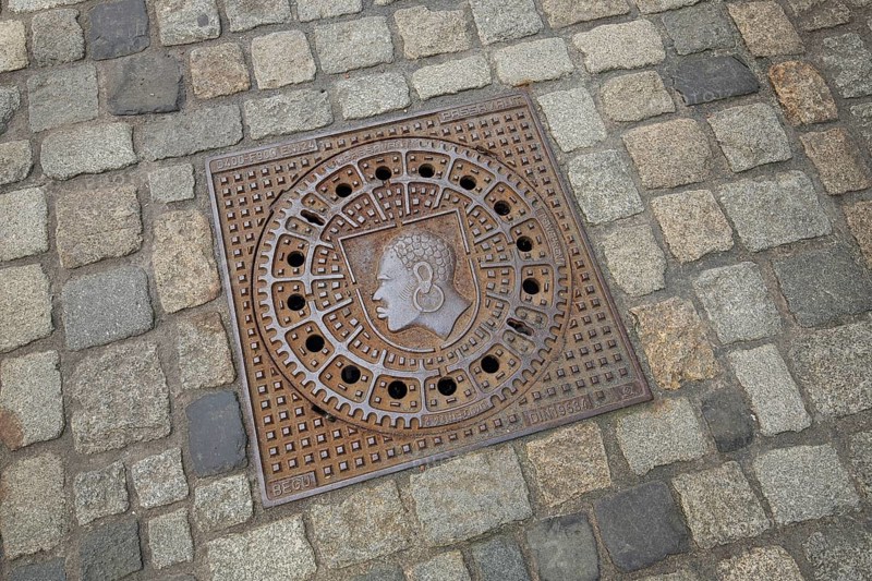 Square manhole cover with city coat of arms, inscription, paving stones, floor, African head with earring, Coburg, Upper Franconia, Franconia, Bavaria, Germany