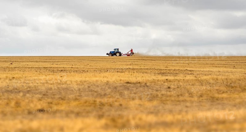 Stormy farmland scenery showing a Tractor on a stubble field in Hohenlohe, an area in Southern Germany at late summer time