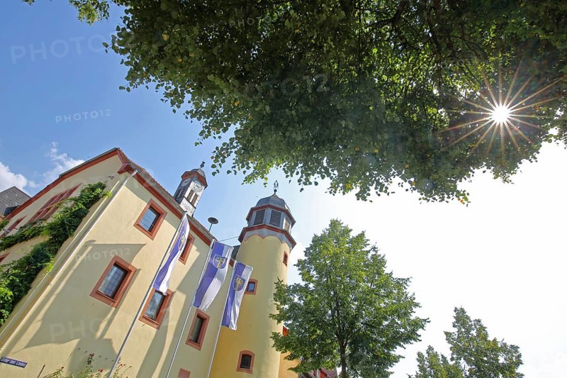 Town hall built in the 16th century with town flag and backlight, view upwards, perspective, Schlüchtern, Vogelsberg, Hesse, Germany
