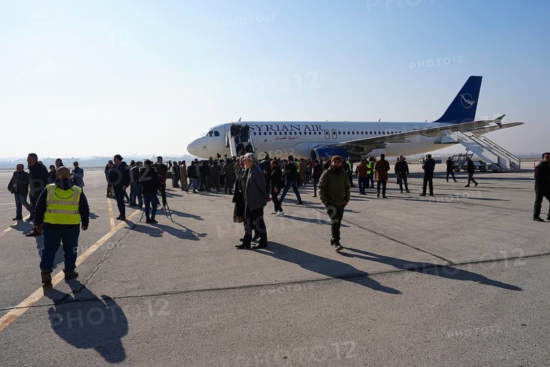 Passengers celebrate with Syrian revolutionary flags as the first flight lands at Aleppo International Airport in the presence of government officials following the fall of Bashar al-Assad's regime. Aleppo, Syria. December 18, 2024, Aleppo, Aleppo, Syria