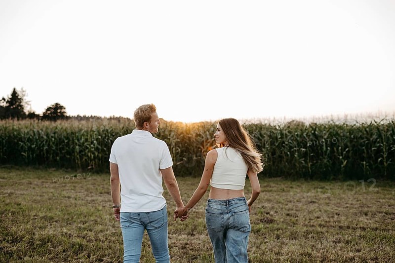 Couple walking hand in hand across a mown field