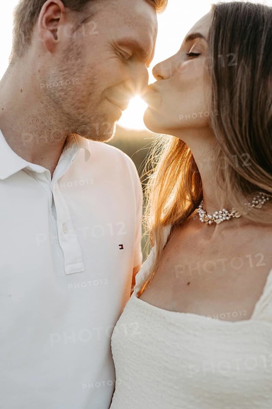 Young couple in love kissing in front of the sunset