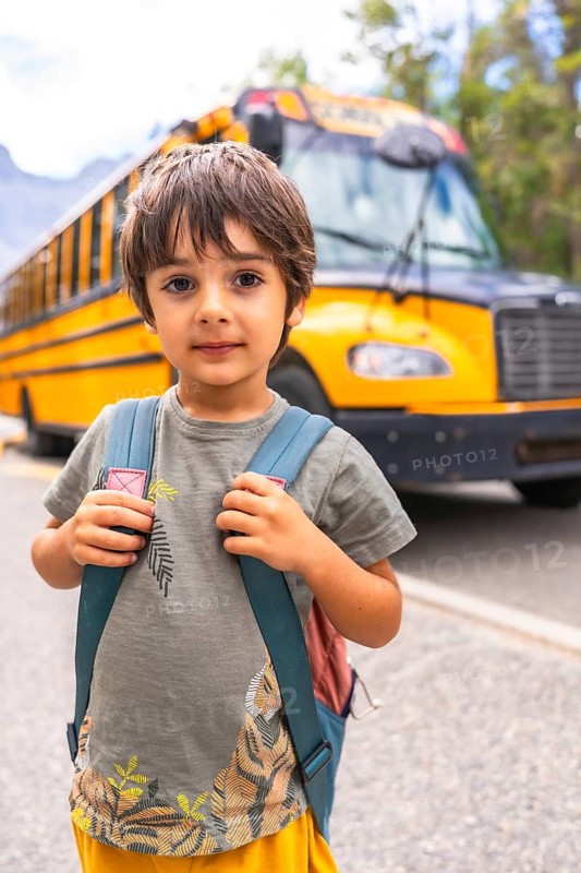 Preschool student carrying backpack and waiting for school bus, excited for first day of class, symbolizing back to school season and childhood education