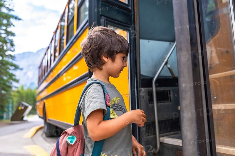 Preschool student entering a school bus, wearing a colorful backpack and beaming with excitement for the first day of class, embodying the joy of back to school adventures and learning