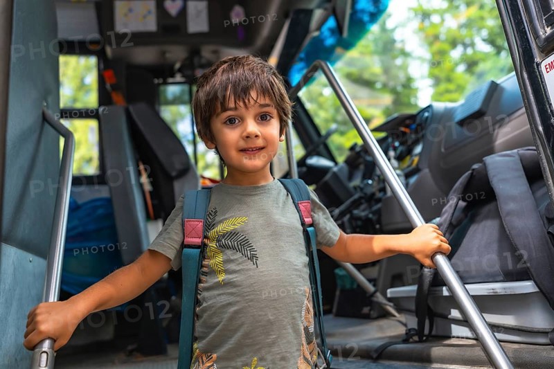 Happy preschool student entering a school bus, gripping the handrail with excitement, embracing the first day of class and the start of a new school year