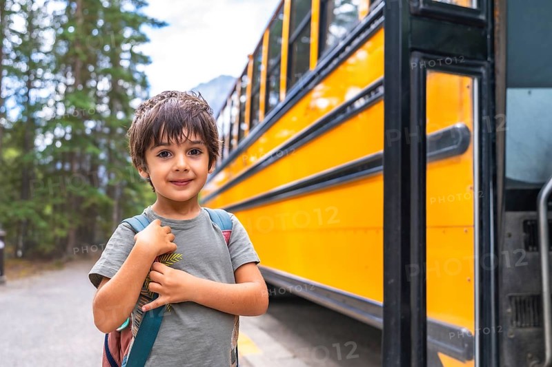 Elementary school student waiting at a mountain road, carrying a backpack and anticipating the arrival of the school bus, excited to embark on a new educational journey