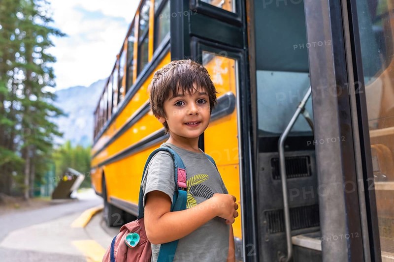 Preschool student with backpack embarking on a yellow school bus, excited for the new academic year, ready to learn and make new friends in elementary school