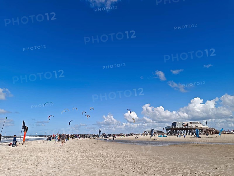 California kitesurfing Masters 2025 on the edge of the Wadden Sea UNESCO World Heritage Site, North Sea, beach, kitesurfing, sport, leisure, spectators, pile dwelling, summer, sun, blue sky, white clouds, Ording, Sankt Peter-Ording, Schleswig-Holstein, Germany