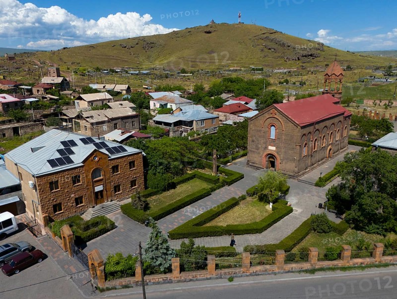 Aerial view of a village with a church and a hill in the background under a blue sky, aerial view, Church of St Mesrop Mashtots, Mesrop Mashtots Church, Oskahan, Oshakan, Ošakan, Aragazotn Province, Armenia