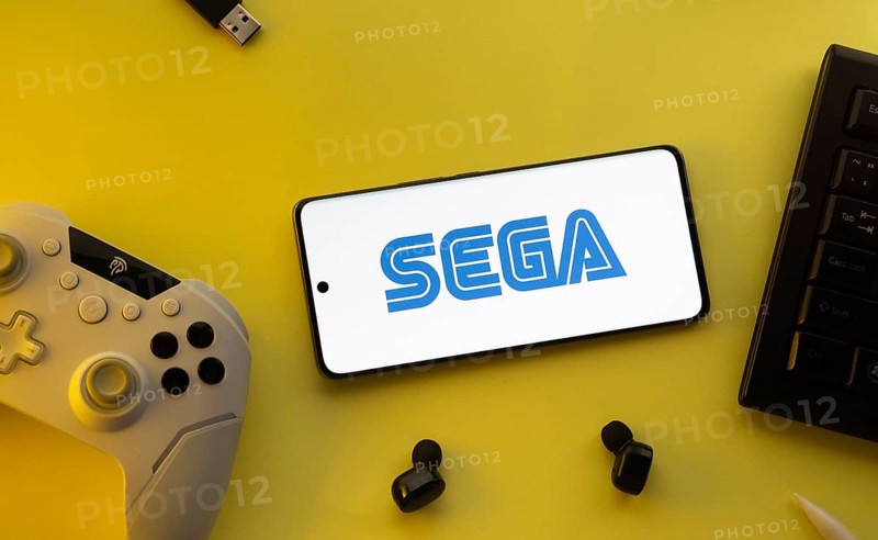 Dhaka, Bangladesh- 13 Sep 2025: Smartphone with Sega logo, game controller, and earbuds on a yellow background